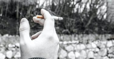 selective color photography of person holding cigarette stick